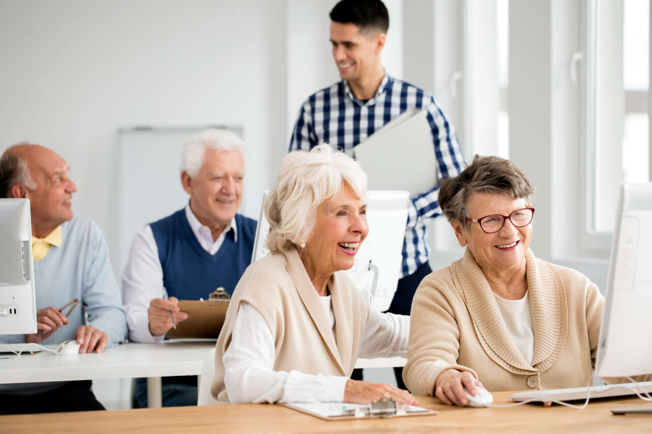 Older adult woman smiling while using a laptop comfortably at home